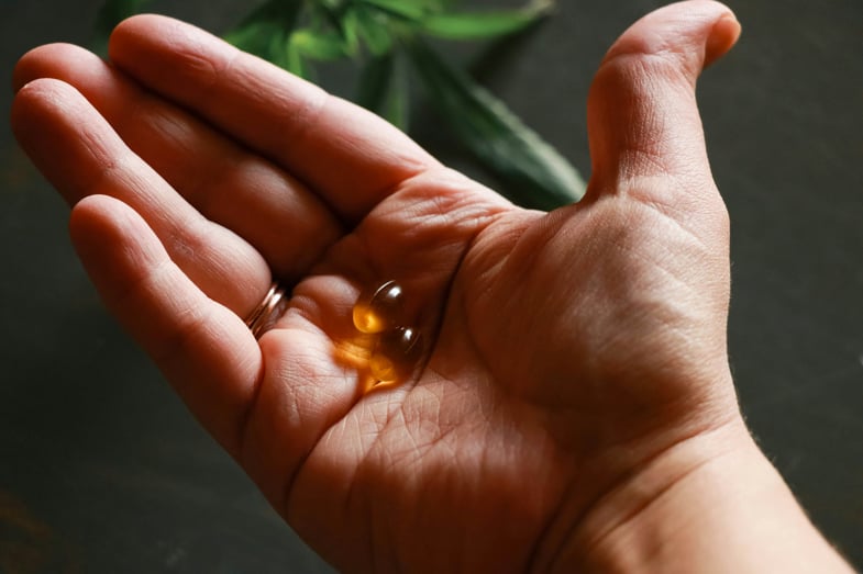 CBD capsules on a man's hand | Justbob