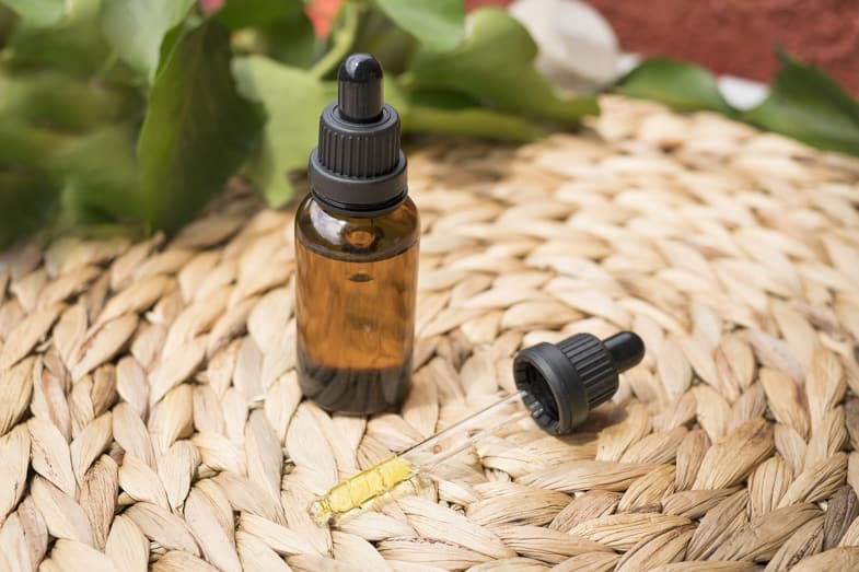 bottle of cbd oil resting on a wicker chair | Justbob