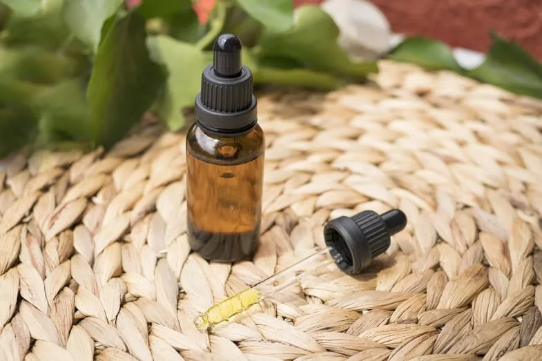 cbd-oil-flask bottle of cbd oil resting on a wicker chair | Justbob