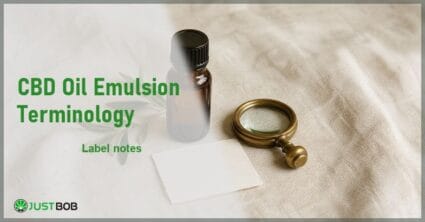 Justbob CBD Oil Emulsion Terminology banner with green title, a CBD oil bottle, a blank label and a brass loupe on cream linen