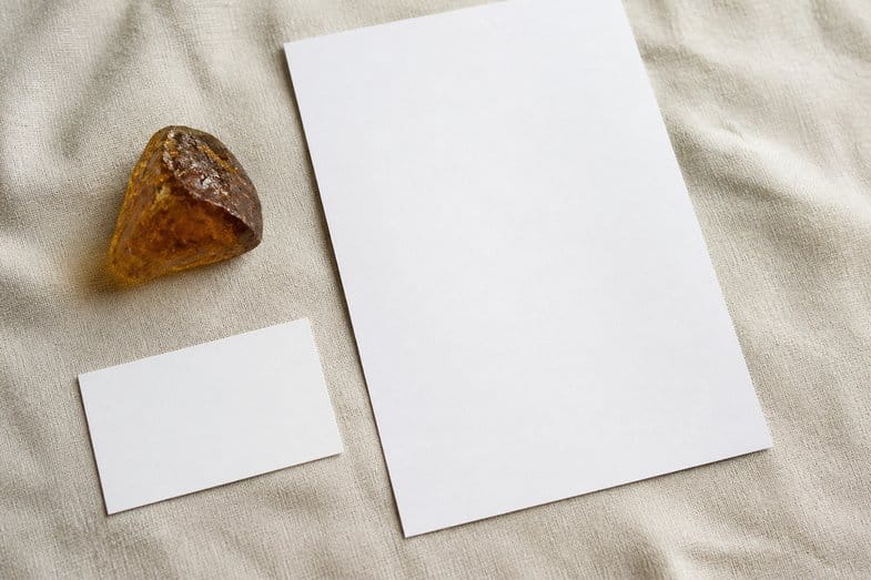 cbd-resin-documents An amber-brown hemp resin piece beside a blank certificate sheet and a blank product card on cream linen