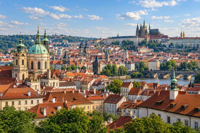 is-weed-legal-in-czech-republic-prague-rooftops A view over the red-tiled rooftops and spires of Prague old town under a bright afternoon sky